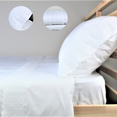 Conjunto de roupa de cama branca com padrão floral em renda em cama de madeira clara