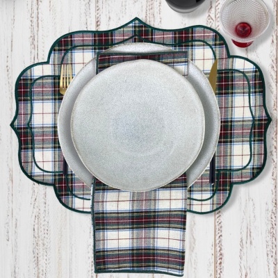 Conjunto de mesa com jogos americanos xadrez, guardanapo, pratos cinza e copo de vinho sobre mesa clara