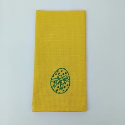 Toalha amarela com bordado verde de ovo decorativo.