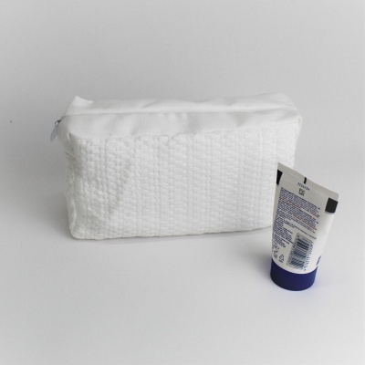 Estojo branco texturizado e tubo com tampa azul sobre fundo branco