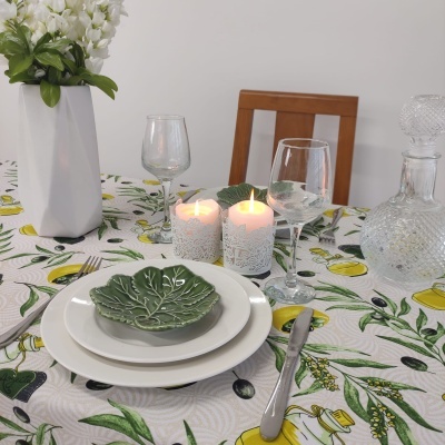 Mesa de jantar posta com pratos, copos, velas acesas, jarra de vidro e vaso com flores