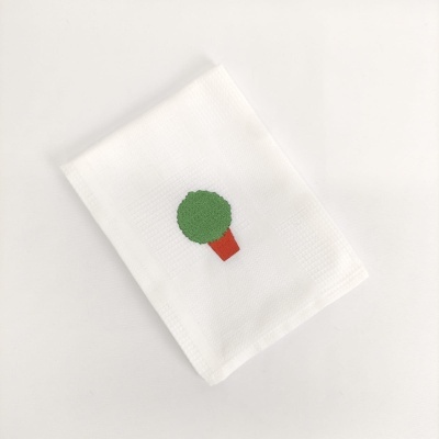 Toalha branca com bordado de árvore verde e castanha
