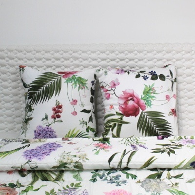 Almofadas e edredão com padrão floral colorido sobre cama com cabeceira branca acolchoada