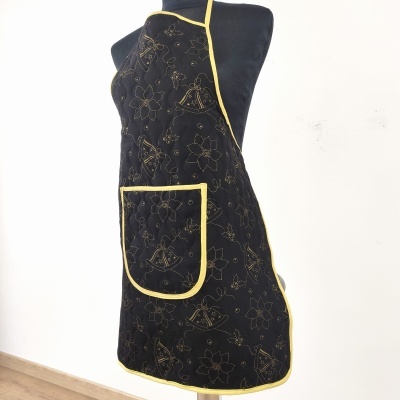 Avental preto com padrões amarelos e bolso frontal em manequim