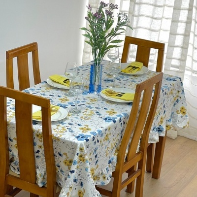 Mesa de jantar com toalha floral e quatro cadeiras de madeira