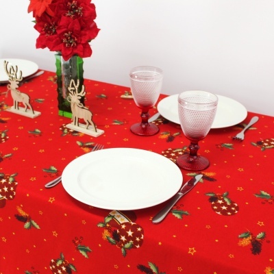 Toalha de mesa vermelha com padrão natalício, copos rosa, pratos brancos e enfeites de rena