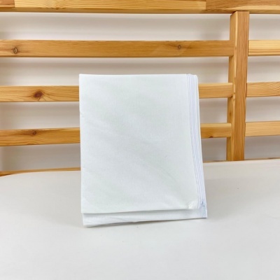 Guardanapo branco de tecido dobrado em suporte de madeira clara com ripas.