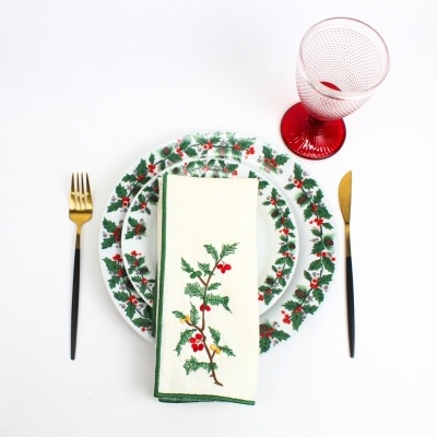 Conjunto de jantar natalício com pratos, guardanapo bordado, talheres dourados e copo vermelho