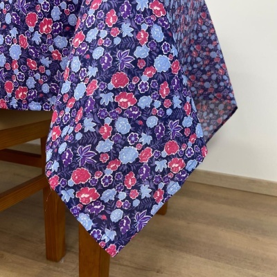 Toalha de mesa azul escuro com padrão floral colorido em mesa de madeira.