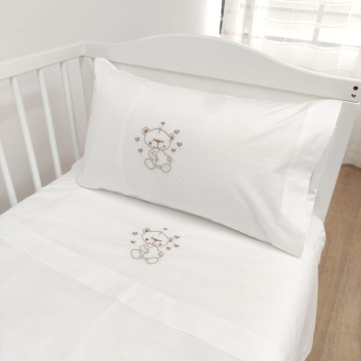 Roupa de cama branca com ursinho bordado no berço branco