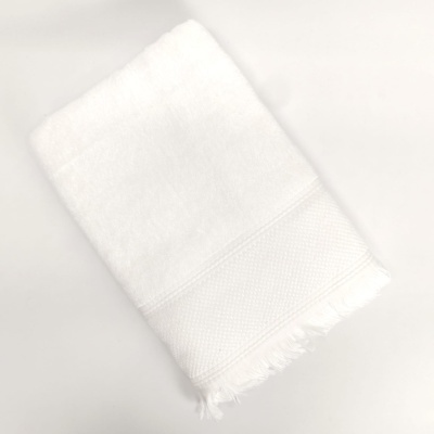 Toalha branca dobrada com franjas na extremidade