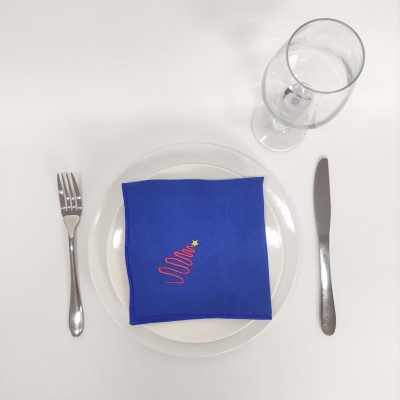 conjunto de jantar com guardanapo azul, pratos brancos, talheres e taça sobre fundo branco