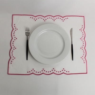 Jogo americano branco com bordas vermelhas, prato branco, garfo e faca com cabos pretos