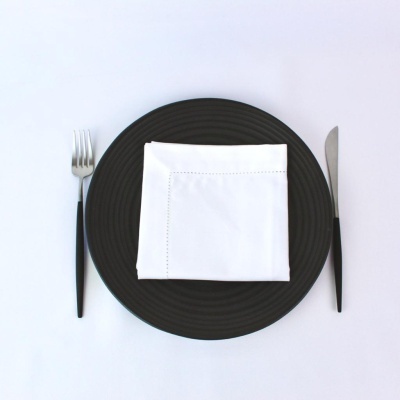Prato preto com guardanapo branco, garfo e faca com cabos pretos