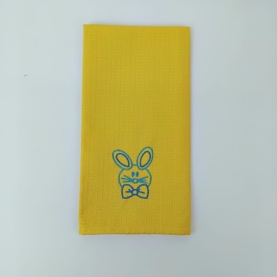 Pano amarelo com bordado azul de coelho de tecido sobre fundo branco