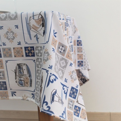 Toalha de mesa branca com padrão de azulejos azul, bege e cinza com desenhos de barcos e flores