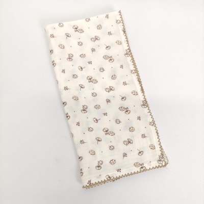 Pano de tecido branco com padrão floral castanho e borda decorativa