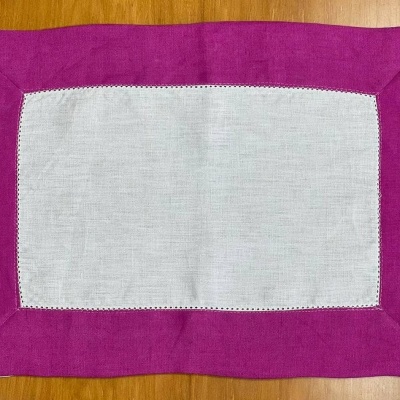 Toalha retangular branca com borda rosa sobre mesa de madeira