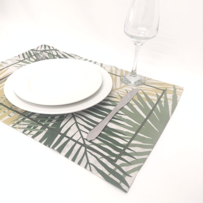 Conjunto de pratos, faca e taça sobre individual com padrão de folhas