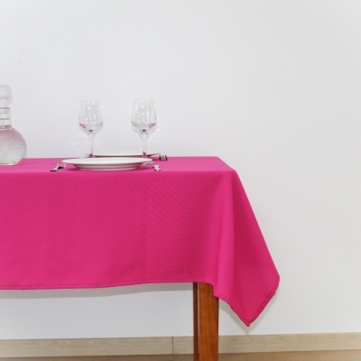 Mesa com toalha rosa, taças, prato e jarro de vidro