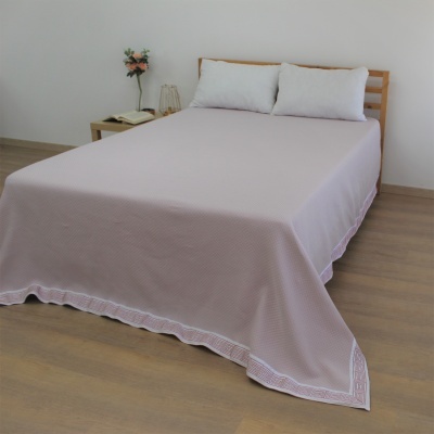 Colcha de cama rosa claro com borda branca decorativa em cama de madeira