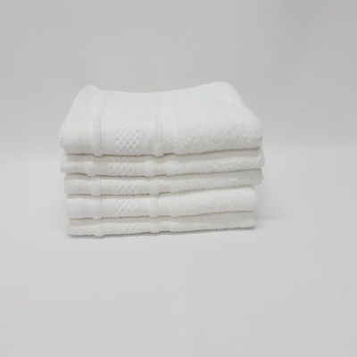 Três toalhas brancas empilhadas com textura e faixas decorativas