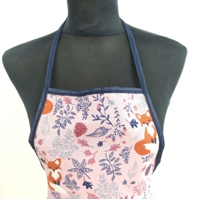 Avental com padrão de raposas e folhagens sobre manequim preto.