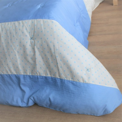 Cobertor azul e branco com desenhos de estrelas sobre chão de madeira