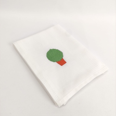 Pano de cozinha branco com bordado de árvore verde e tronco castanho.