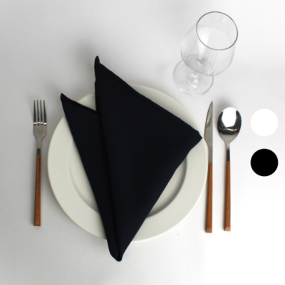 Conjunto de jantar com prato branco, guardanapo preto, talheres com cabos de madeira e copo de vidro numa mesa com toalha branca