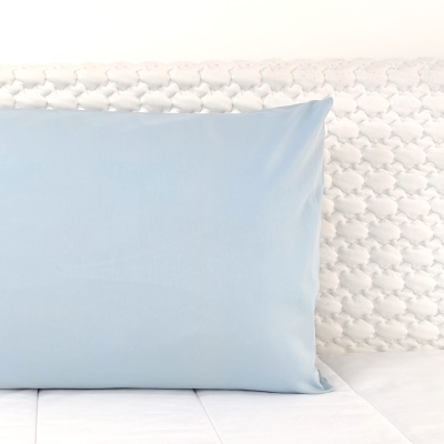 Almofada azul claro lisa encostada em parede branca com padrão 3D oval