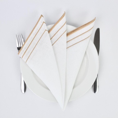 Guardanapo branco com riscas douradas dobrado no prato com talheres