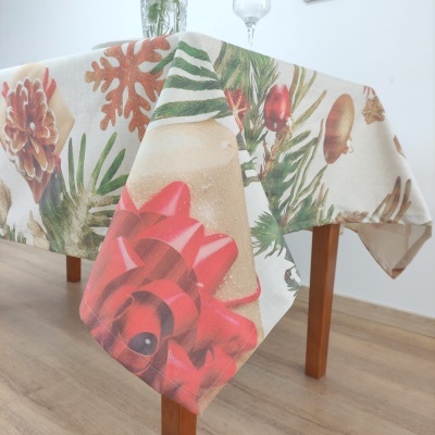 Toalha de mesa natalícia com pinhas, laço vermelho, folhas verdes e sinos dourados.