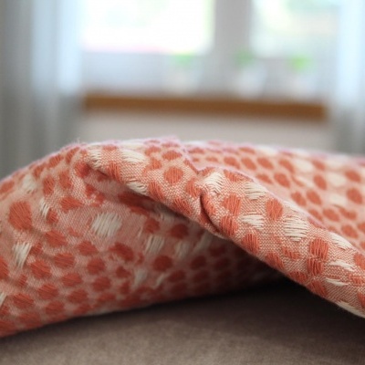 tecido com padrão de bolinhas cor de laranja e branco sobre superfície cinza