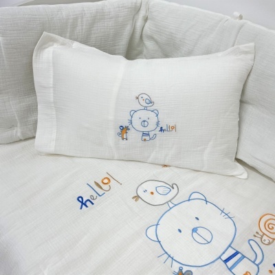 Conjunto de almofada e colcha branca com bordados de ursinhos e passarinhos e a palavra 'hello!'