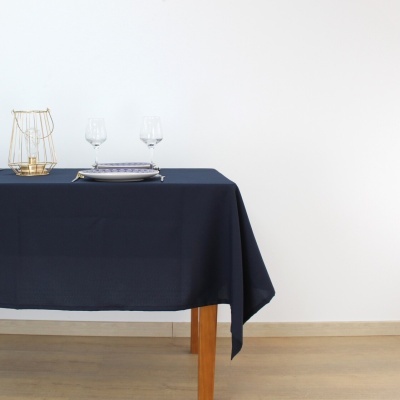 Mesa com toalha azul escura, pratos, copos de vinho e castiçal dourado