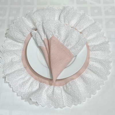 Guardanapo rosa com base branca rendada em prato branco sobre toalha branca