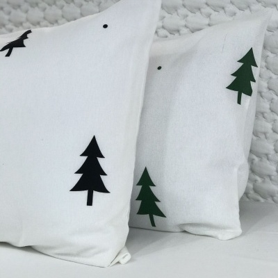 Duas almofadas brancas com pinheiros decorativos preto e verde