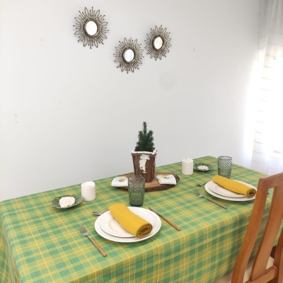 Mesa de madeira com toalha xadrez verde e amarela e decoração simples com pratos e guardanapos amarelos