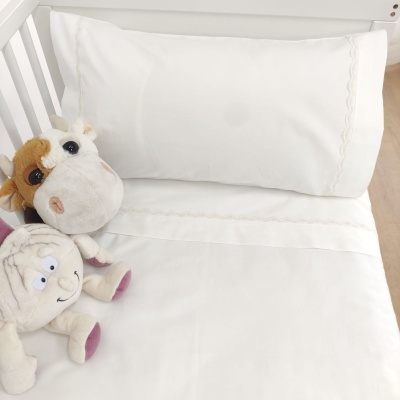 Lençol branco com bordado delicado e dois peluches em berço branco