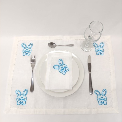 Jogo americano branco com desenhos de coelhos azuis e talheres com prato.