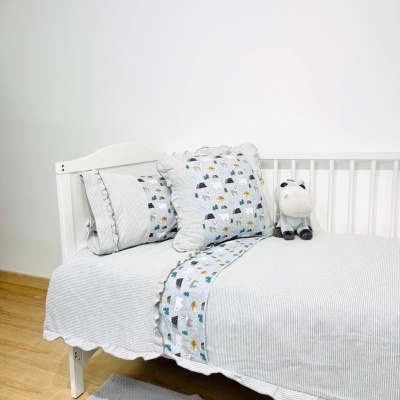 Cama branca de criança com roupa de cama cinza clara e detalhes de padrão colorido com peluche de unicórnio