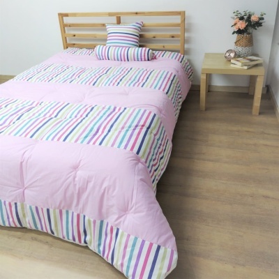 Conjunto de cama rosa com riscas coloridas e almofada, cama de madeira clara, mesa com flores e relógio