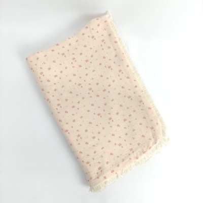 Lençol creme com pequenas flores cor-de-rosa e franjas nas bordas