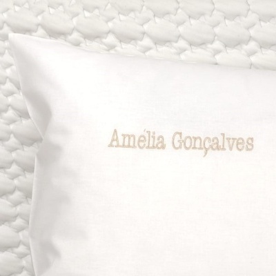 Travesseiro branco bordado com nome em sobre manta branca texturizada