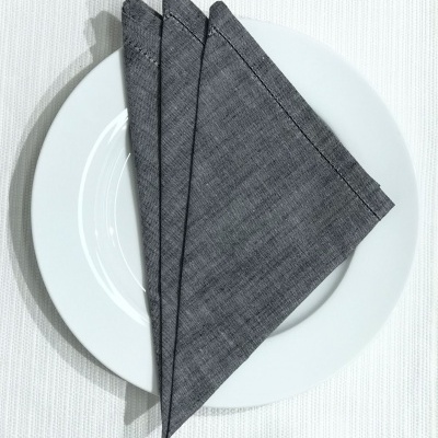 Guardanapo de tecido cinzento dobrado em prato branco