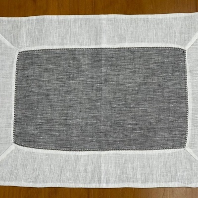 Toalha de mesa retangular cinza e branca colocada sobre superfície de madeira.