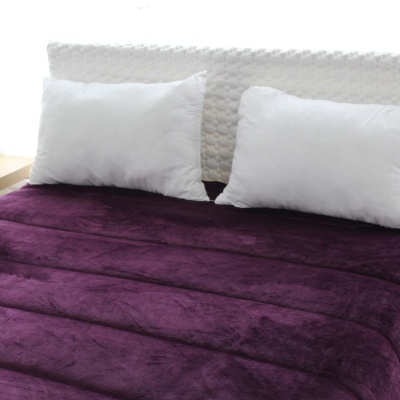 Cama com colcha roxa escura e duas almofadas brancas