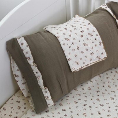 Detalhe de cama com roupas de cama estampadas castanhas e brancas