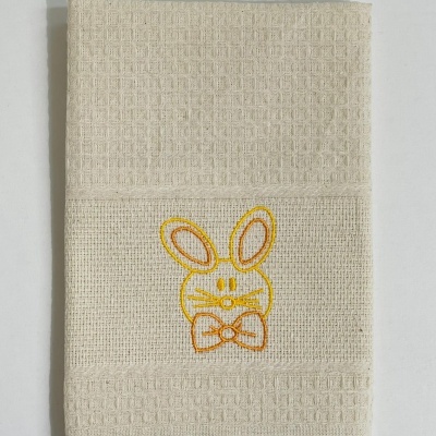 Toalha creme com bordado de coelho amarelo e laranja